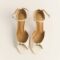 Cream open-toe high-heeled sandals with ankle straps and a jeweled circular ornament at the front.