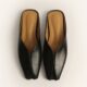 Pair of black leather slip-on mules with tan insoles, viewed from above on a light background.